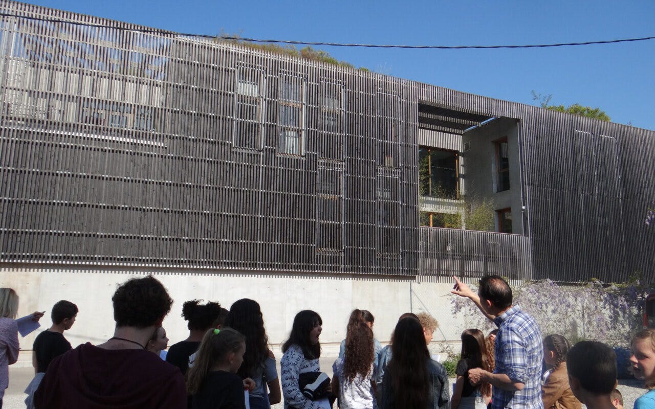 Groupe d'élèves en visite devant un bâtiment d'architecture contemporaine